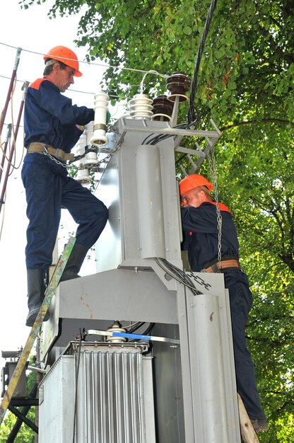 Elektriker ersetzen einen defekten Isolator in einem Umspannwerk