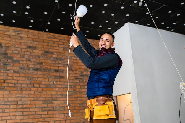 Elektriker-Installateur mit einem Werkzeug in den Händen, der auf der Baustelle mit Kabeln arbeitet. Reparatur- und Handwerkerkonzept. Haus und Hausumbau.