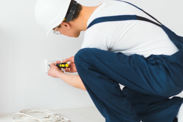 Elektriker installiert dekorativen Rahmen an Strom- und TV-Steckdosen