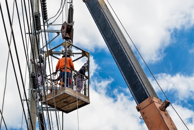 Elektriker ist in einem Korb auf einem Strommast, um Drähte zu installieren und zu reparieren.