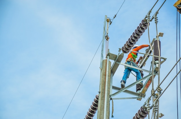 Elektriker klettern auf Strommasten, um Stromleitungen zu installieren und zu reparieren