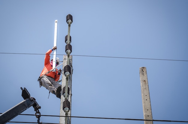 Elektriker klettern auf Strommasten, um Stromleitungen zu installieren und zu reparieren