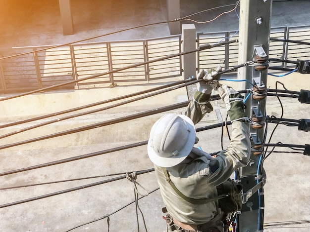 Elektriker klettern auf Strommasten, um Stromleitungen zu verlegen.