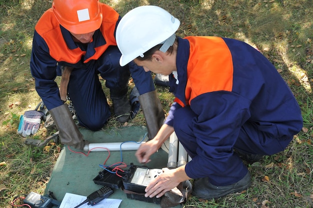 Elektriker prüfen die Funktionsfähigkeit einer Keramiksicherung mit einem mechanischen Ohmmeter