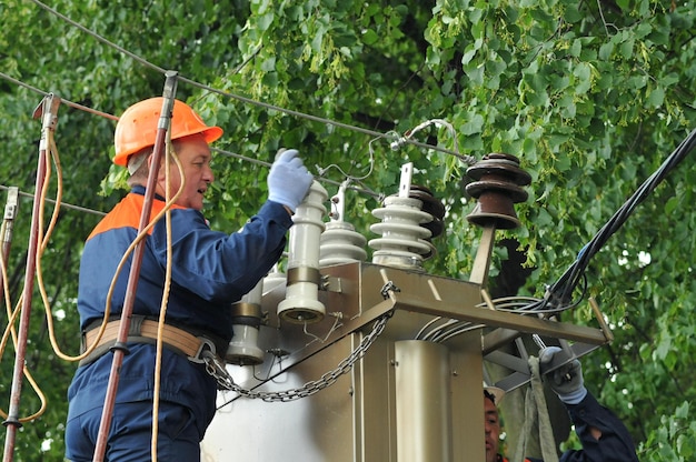 Elektriker reparieren und ersetzen den beschädigten Isolator im elektrischen Schaltschrank.