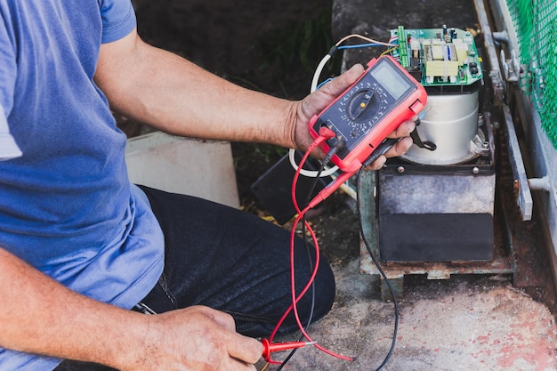 Foto elektriker überprüft das mainboard mit multimeter im freien bei