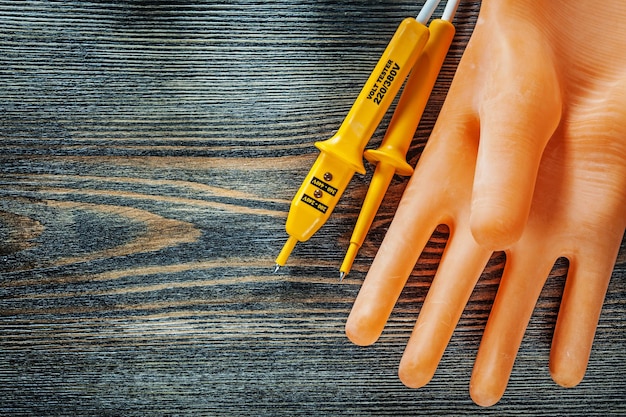 Elektrikerhandschuhe elektrischer Tester auf Holzbrett.