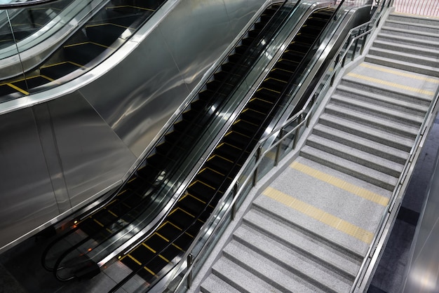 Elektrische Rolltreppen und normale Treppen in der U-Bahnstation. Einfacher und bequemer Gehweg in Gemeinschaftszentren, Einkaufszentren, Plazas, Flughafenterminals oder U-Bahnen.