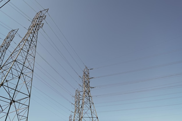 Elektrische Stromleitungen, die Energie mit einem elektrischen Turm auf Hintergrundspannung des blauen Himmels erzeugen