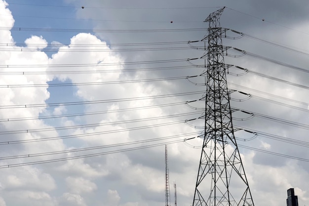 Elektrischer Hochspannungs-Übertragungsturm auf Nimbuswolken im Himmelshintergrund.