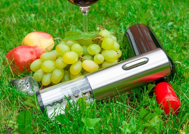 Elektrischer Korkenzieher auf dem Gras In der Nähe des Korkbelüfters und einer Flasche Wein im Hintergrund