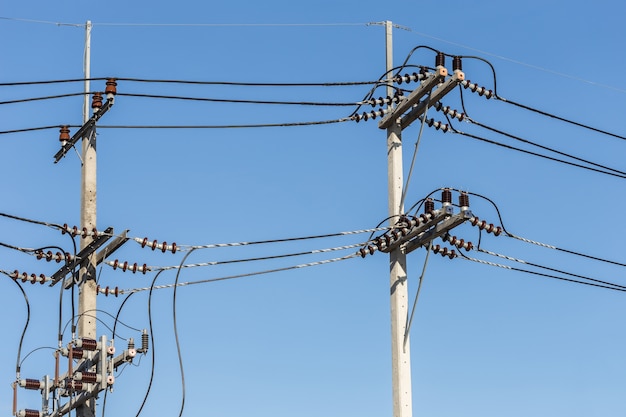 Elektrischer Pfosten schließen elektrische Drähte der hohen Spannung auf Hintergrund des blauen Himmels an
