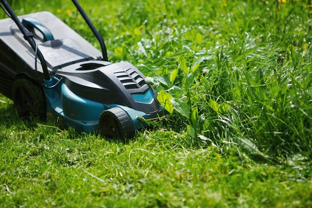 Elektrischer Rasenmäher für grünes Gras. Der Unterschied zwischen den bearbeiteten und bewachsenen Teilen des Feldes.