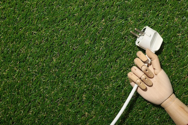 Elektrisches Kabel in der Hand einer Mannequin auf dem Gras