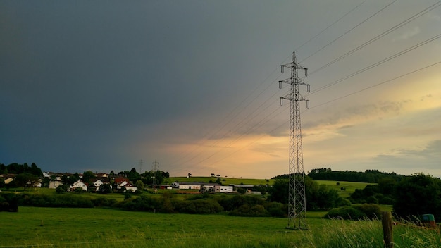 Elektrizitätsmast auf dem Feld gegen den Himmel bei Sonnenuntergang