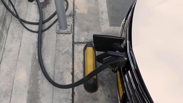 Foto elektrofahrzeug oder ev-fahrzeug parkplatz an der ladestation und angeschlossene stromversorgung strom auf die ev- oder hybridfahrzeugbatterie grüne energie und öko-kraft der welt zukünftige transport ev-kraft