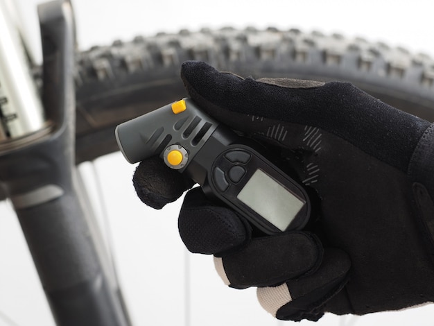 Elektronisches Manometer zur Messung des Fahrradreifendrucks in der Hand eines männlichen Radfahrers.