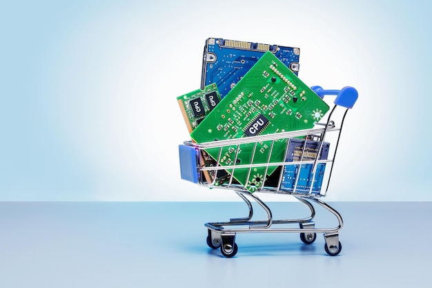 Elementos de chips electrónicos y tablero en carrito de compras sobre fondo azul con espacio de copia
