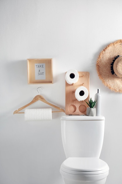 Foto elementos de decoración necesarios y taza del inodoro cerca de la pared blanca interior del baño