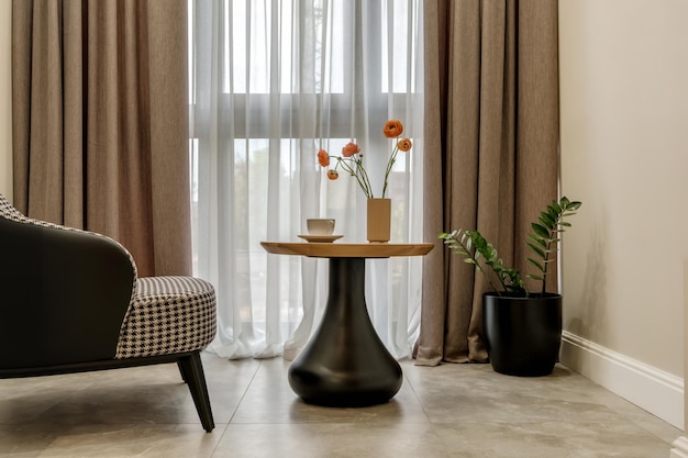 Elementos decorativos de la habitación de invitados y sala de descanso con una mesa de té, un sillón y un ramo de flores y una taza de café