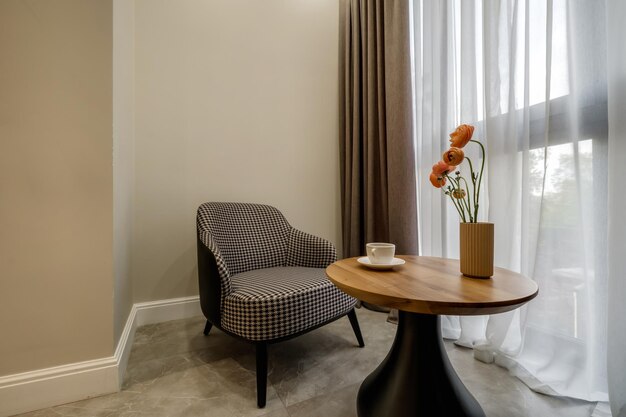 Elementos decorativos de la habitación de invitados y sala de descanso con una mesa de té, un sillón y un ramo de flores y una taza de café