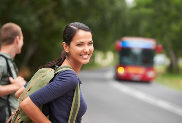 Eles ainda estavam se acostumando com as estradas Uma bela jovem vestindo uma mochila enquanto esperava um ônibus com o marido