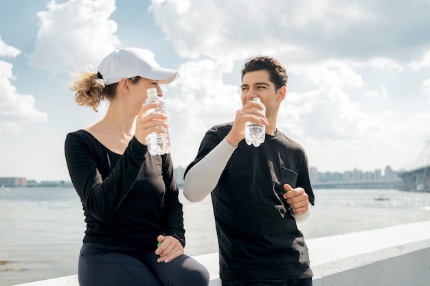 Eles bebem água limpa de garrafas plásticas Os atletas ficam felizes em se preparar para o treinamento