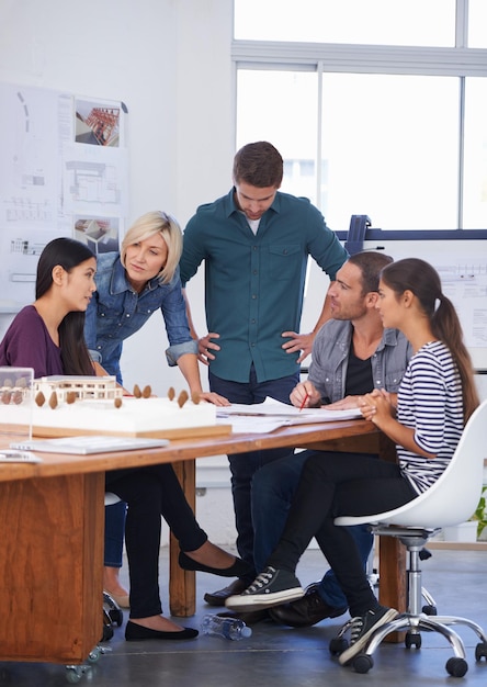 Eles ouviram atentamente a solução dela Foto recortada de um grupo de arquitetos discutindo um modelo em escala