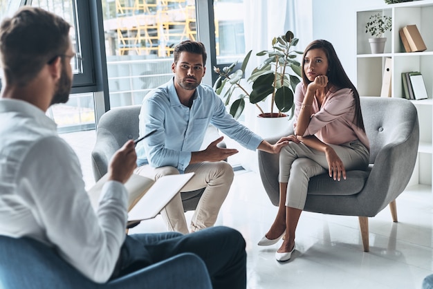 Eles precisam de um conselho. Jovem casal conversando enquanto está sentado na sessão de terapia