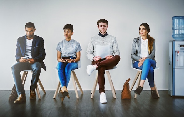 Eles têm as ferramentas para prepará-los para o sucesso Foto de um grupo de jovens empresários esperando na fila para uma entrevista de emprego