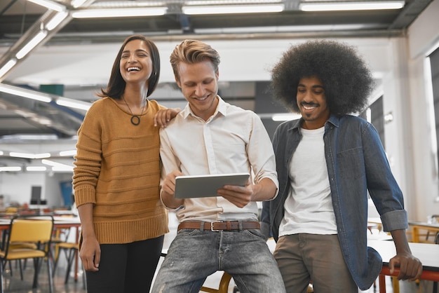 Eles têm uma ótima relação de trabalho foto recortada de três jovens empresários olhando para um tablet em seu escritório