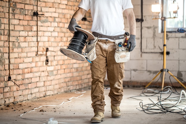 Eletricista com ferramentas, trabalhando em uma construção