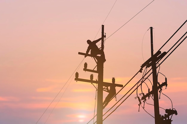 Foto eletricista de silhueta trabalhando em equipamentos de instalação de poste de alta tensão