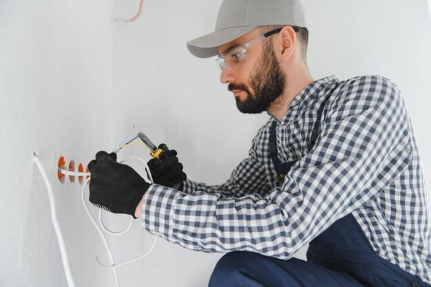 Foto eletricista instala caixas de tomadas na parede e coloca uma massa nelas