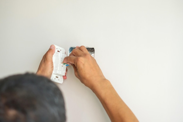 Eletricista instalando cabos de fio para plugue de soquete em um serviço de reparo de renovação de concreto e desenvolvimento de conceitos de casa e apartamento