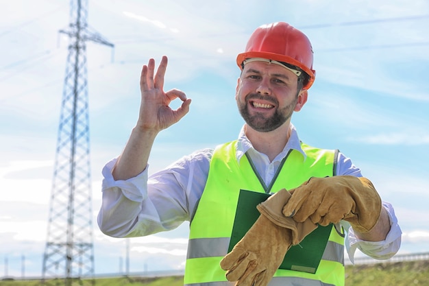 Eletricista trabalhando em um capacete usando luvas de pé em um campo