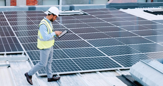 Eletricista verificando a tecnologia de painéis solares no telhado do prédio em que está trabalhando Técnico de engenheiro profissional usando um capacete de segurança olha atentamente para seu design moderno de energia renovável