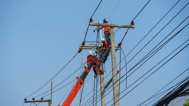 Eletricistas trabalham em torres de alta tensão para instalar fios e equipamentos.