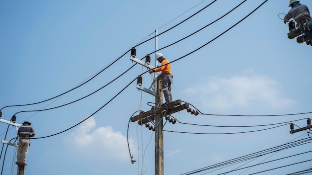 Eletricistas trabalham em torres de alta tensão para instalar novos fios e equipamentos.