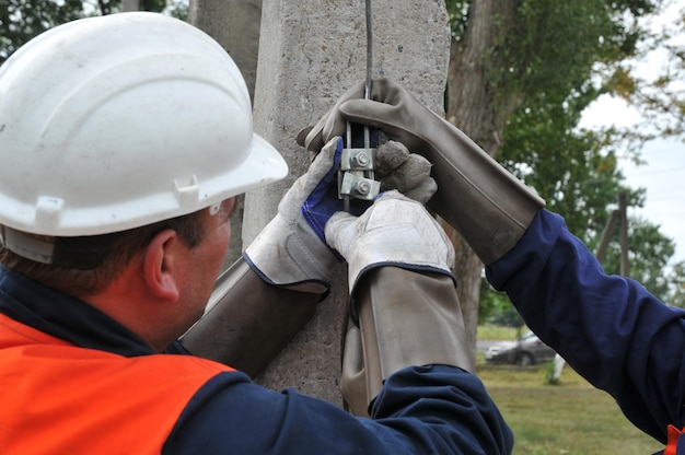 Eletricistas verificam a condição do solo no poste elétrico