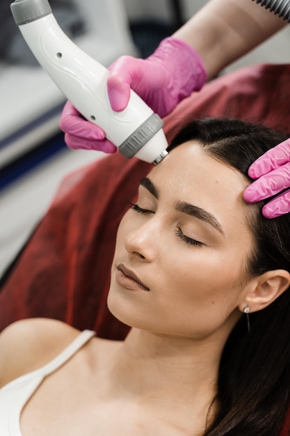 Elevação por radiofrequência para mulheres jovens Dermatologista está fazendo um lifting de pele por radiofrequência O facelift por RF firma e alivia a flacidez da pele