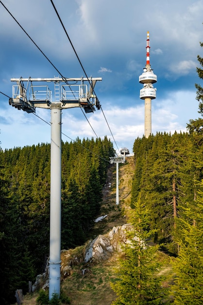 Elevador com cabo passa entre a floresta de abetos no pico contra o pano de fundo das cadeias montanhosas das montanhas rhodope