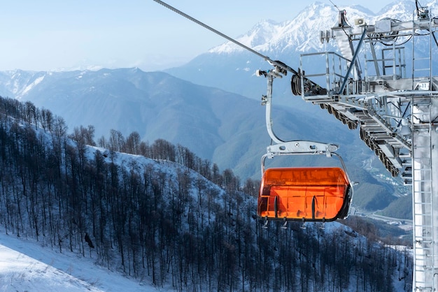 Elevador de cadeira de esqui laranja brilhante vazio no inverno das montanhas contra a neve Esqui alpino e snowboard