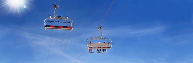 Elevador de esqui no céu azul com o sol em vista panorâmica