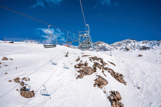 Elevador de esqui sobre a montanha coberta de neve cênica contra o céu