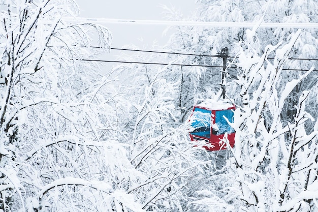 Elevador de gôndola na estância de esqui na floresta de inverno durante a queda de neve