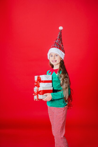 Elfenmädchen mit Geschenken Weihnachtsmann-Helfer auf einem hellroten hellen farbigen Hintergrund Kopienraum