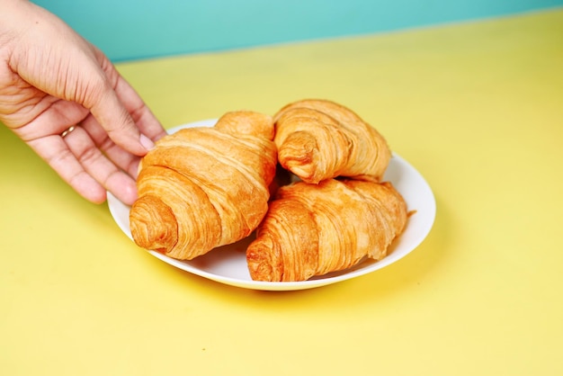 Elija a mano un croissant recién horneado de un plato