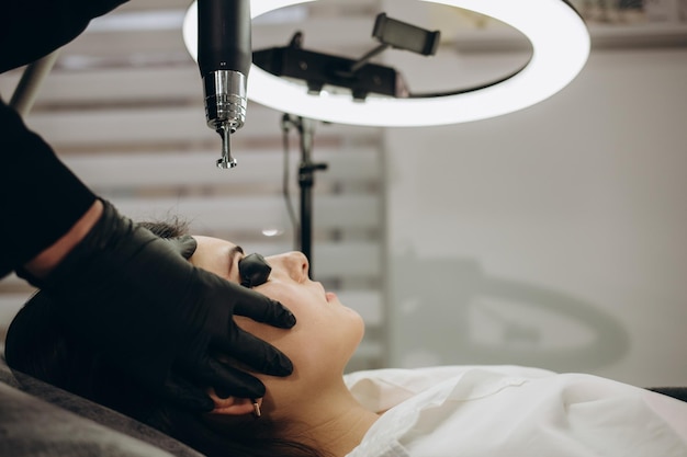 Eliminación láser de maquillaje permanente La esteticista elimina el tatuaje de las cejas