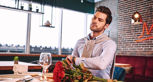 Foto ella debería estar pronto, el hombre se está preocupando mientras espera en el restaurante.